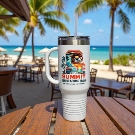 White tumbler with a colorful design on a wooden table at a beachside cafe.